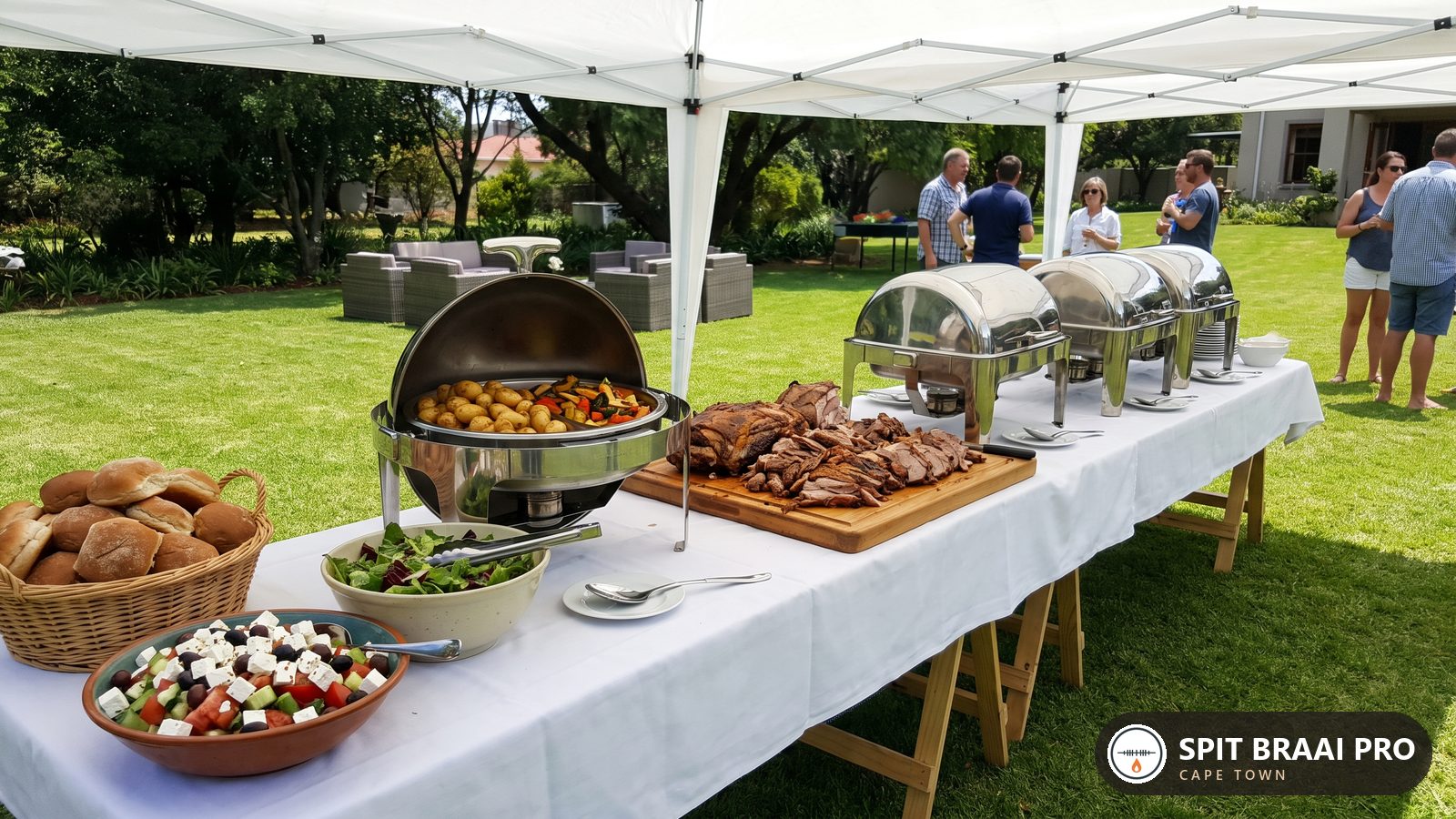 Outdoor catering buffet with carved spit-roast meat, roast potatoes and salads